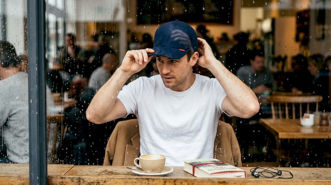 Man styles premium cap in rainy New Zealand cafe
