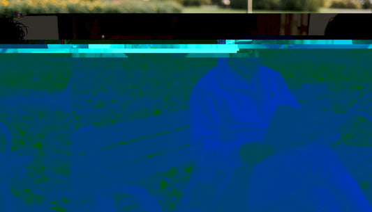 Man wearing premium cap reading on park bench