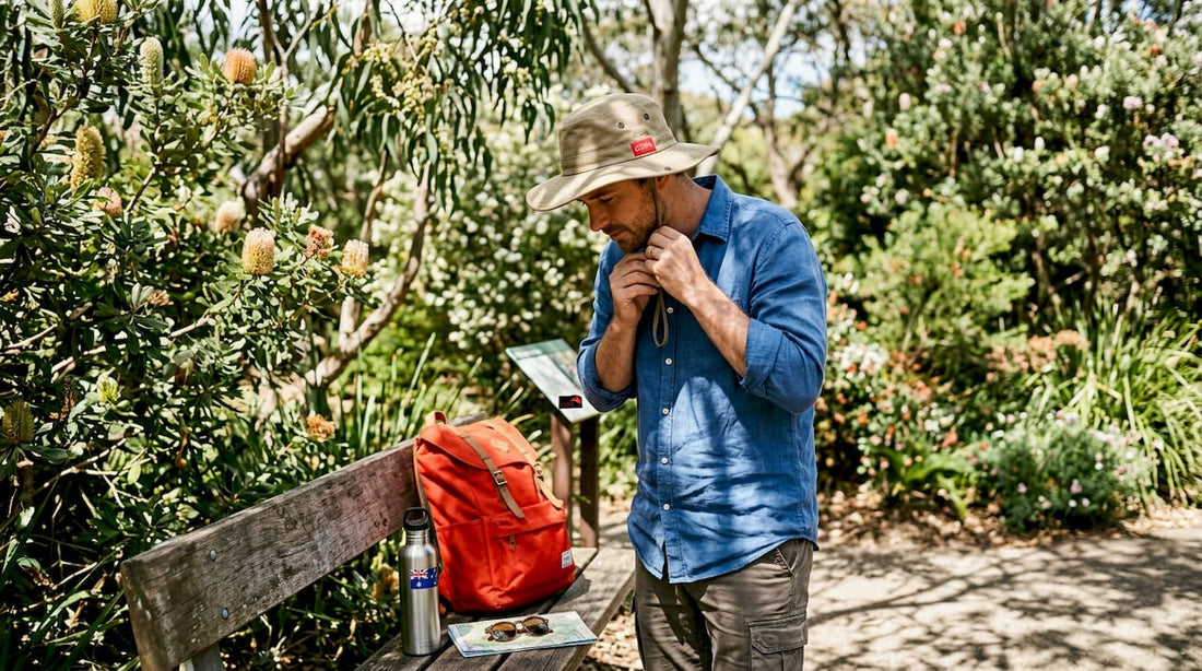 Man testing wide-brim sun hat fit in park