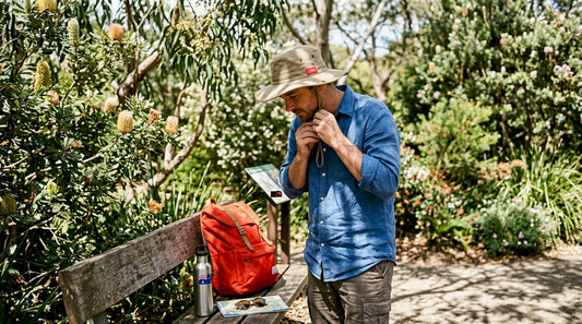 Man testing wide-brim sun hat fit in park