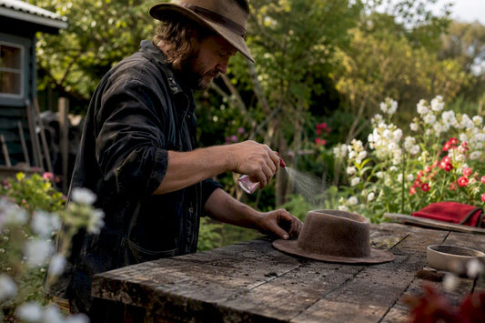 Craftsman spraying wool hat in workshop