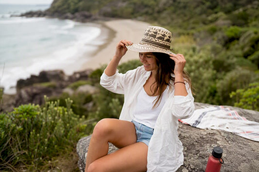 Person adjusting mesh sun hat at NZ coast
