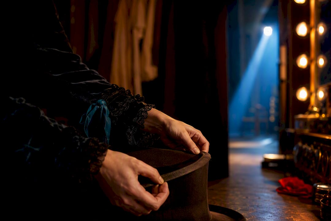Performer handling a cropped theatrical fedora