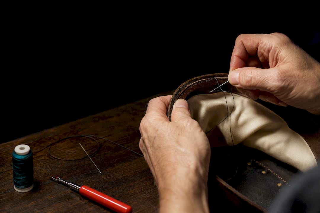 Hands stitching a replacement hat sweatband