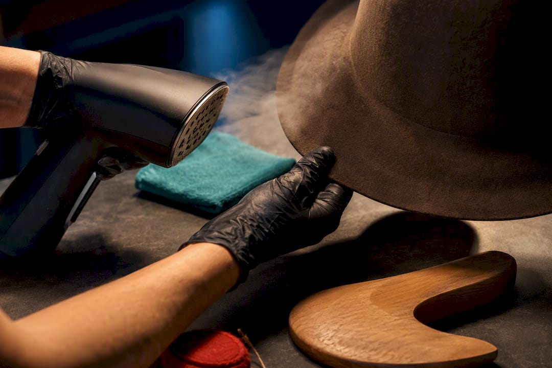 Gloved hands steaming a fedora brim