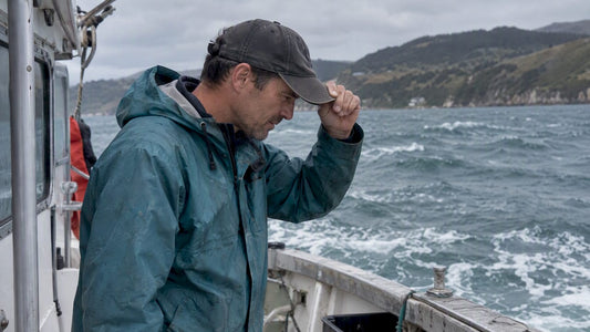 Boater holding cap against coastal wind